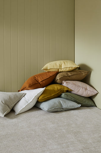 a pile of cushions from The Loom Collection online store in Dubai. The cushions are placed randomly in a room corner and they are multiple neutral colors